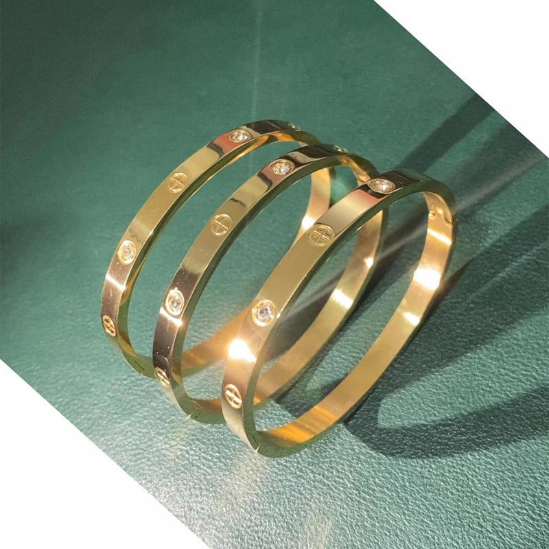 Pulsera y brazalete contemporáneo de cruz con clavo tipo tuerca en zirconia dorada 2023 para mujer en acero inoxidable.