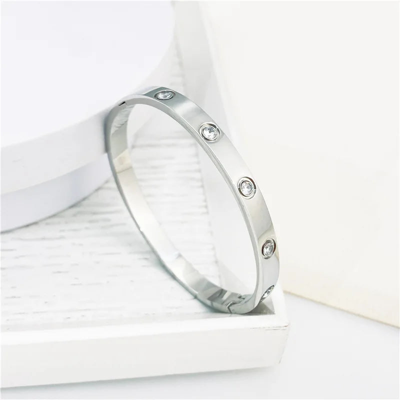 Pulsera y brazalete contemporáneo de cruz con clavo tipo tuerca en zirconia dorada 2023 para mujer en acero inoxidable.