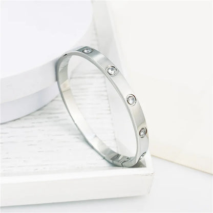 Pulsera y brazalete contemporáneo de cruz con clavo tipo tuerca en zirconia dorada 2023 para mujer en acero inoxidable.