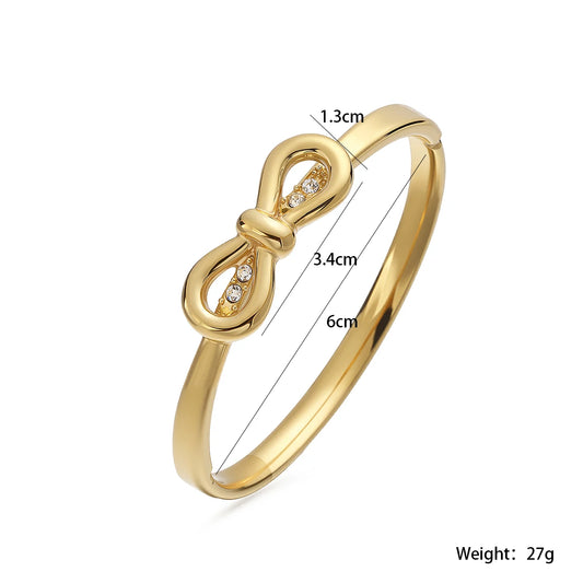 Brazalete minimalista tipo cuff (abierto) con lazo de nudo en acero inoxidable chapado en oro, con detalles de zirconia, resistente al agua, joyería apilable para mujer.