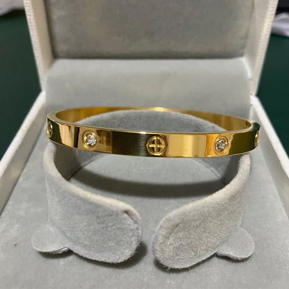 Pulsera y brazalete contemporáneo de cruz con clavo tipo tuerca en zirconia dorada 2023 para mujer en acero inoxidable.