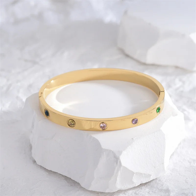 Pulsera y brazalete contemporáneo de cruz con clavo tipo tuerca en zirconia dorada 2023 para mujer en acero inoxidable.