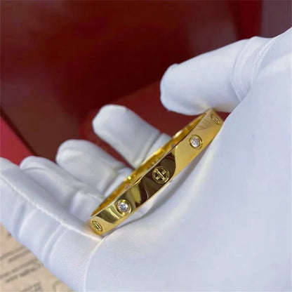 Pulsera y brazalete contemporáneo de cruz con clavo tipo tuerca en zirconia dorada 2023 para mujer en acero inoxidable.
