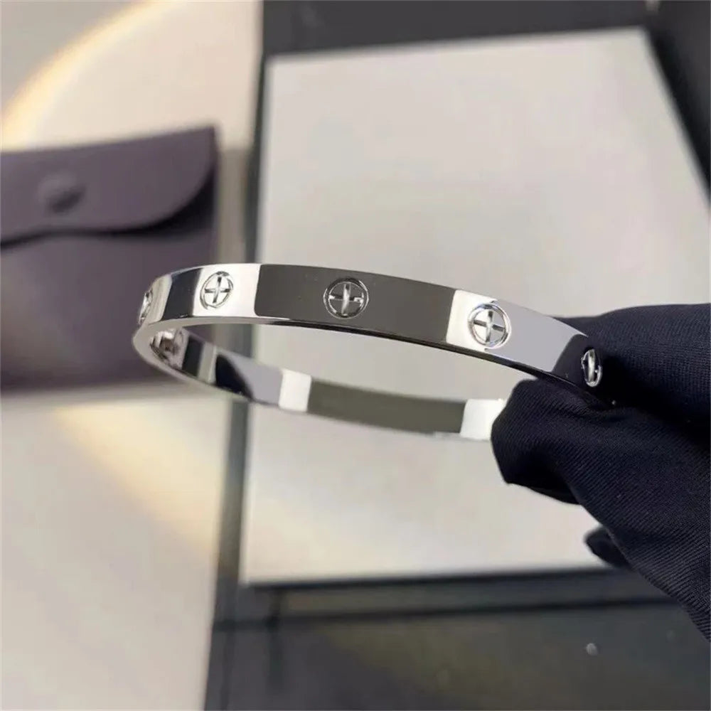 Pulsera y brazalete contemporáneo de cruz con clavo tipo tuerca en zirconia dorada 2023 para mujer en acero inoxidable.