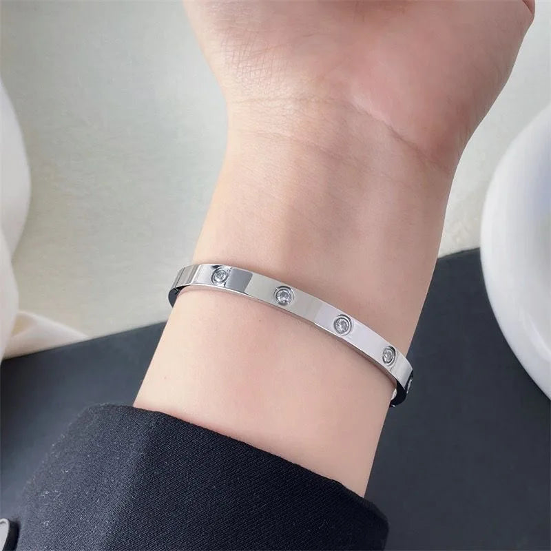 Pulsera y brazalete contemporáneo de cruz con clavo tipo tuerca en zirconia dorada 2023 para mujer en acero inoxidable.